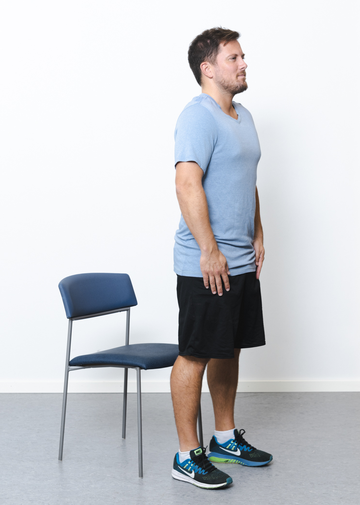 Patient stående oprejst foran stol