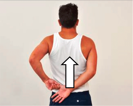 Mand stående med begge hænder bagved ryggen. Den ene hånd har fat i den andens tommelfinger.