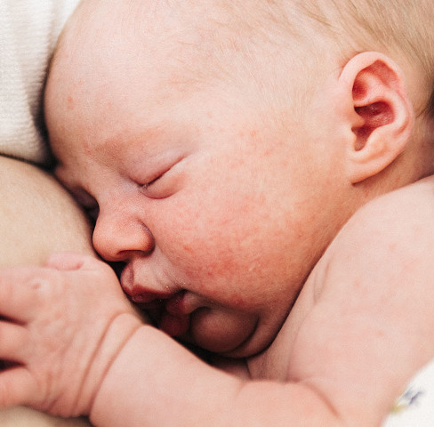 Nyfødt baby ligger hud-mod-hud med forælder