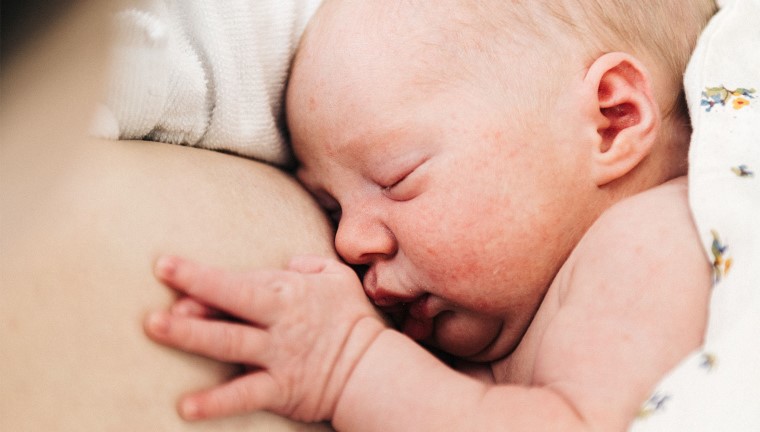 Nyfødt baby ligger hud-mod-hud med forælder