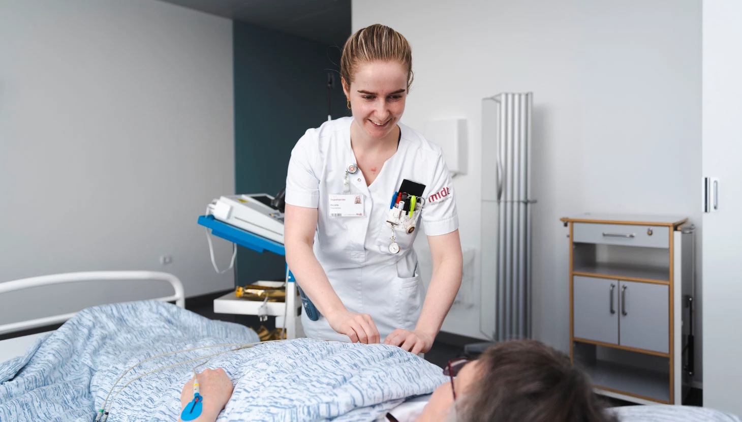 Sygeplejerske tilser en liggende patient